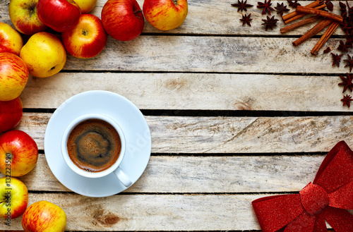 Some red and yellow apples, Festive red bow, kitchen herbs and cup of coffee on the white wooden table. food and dietary concept. picture with free space for text