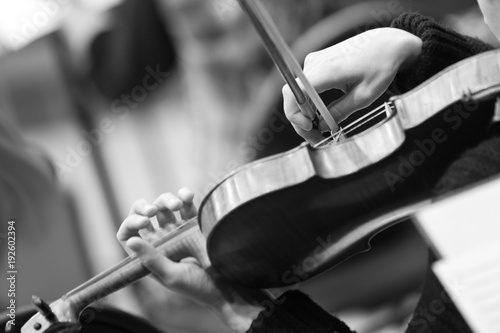Hands of a girl playing the violin closeup in black and white tones