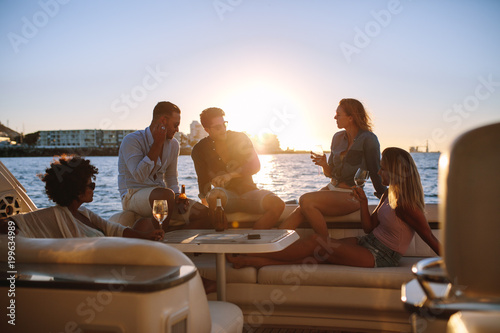 Group of friends partying on yacht at sunset