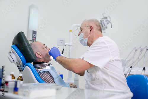 Adult dentist treats grandpa's teeth in dental clinic