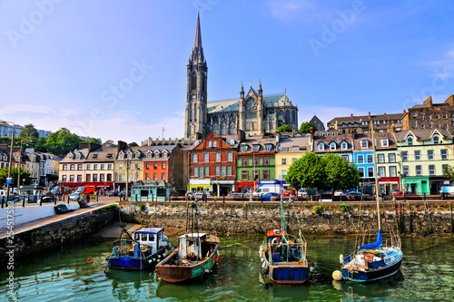 Colorful buildings and old boats with cathedral in background in the harbor of Cobh, County Cork, Ireland