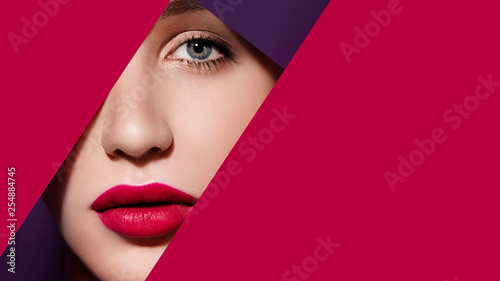 Plump bright red lips in red and violet paper frame. Young model face. Close up beauty photo. Geometry and minimalism. Creative fashion makeup, beautiful woman, clear skin