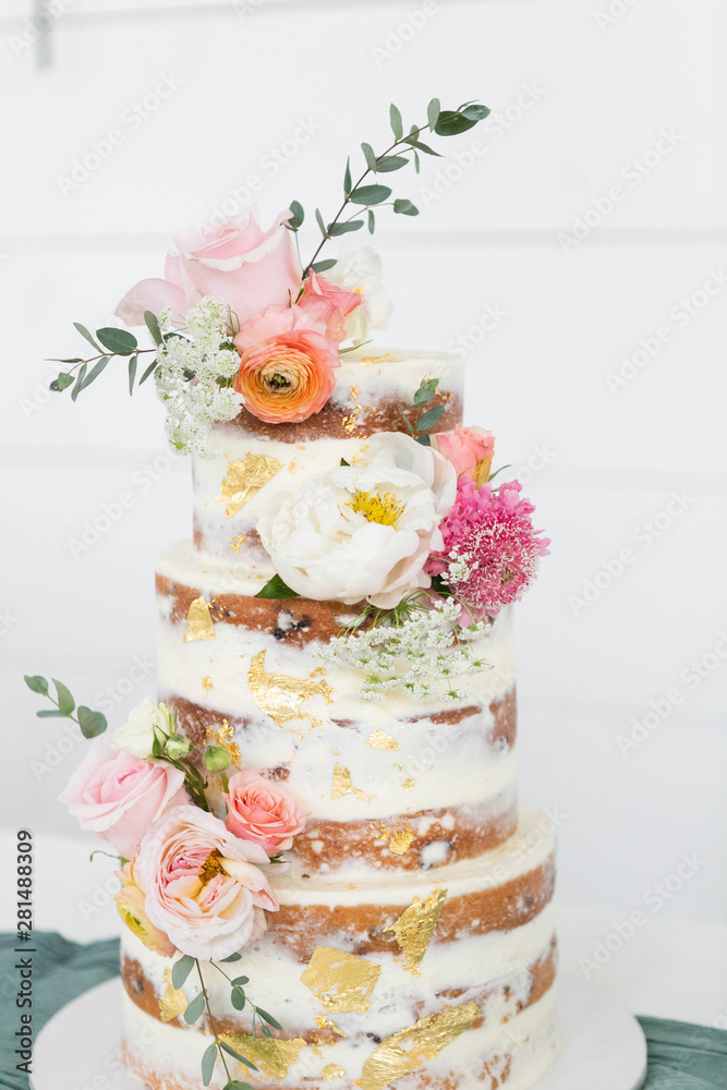 Naked Wedding Cake Decorated With Gold Foil And Flowers Three Tiered Cake White Background