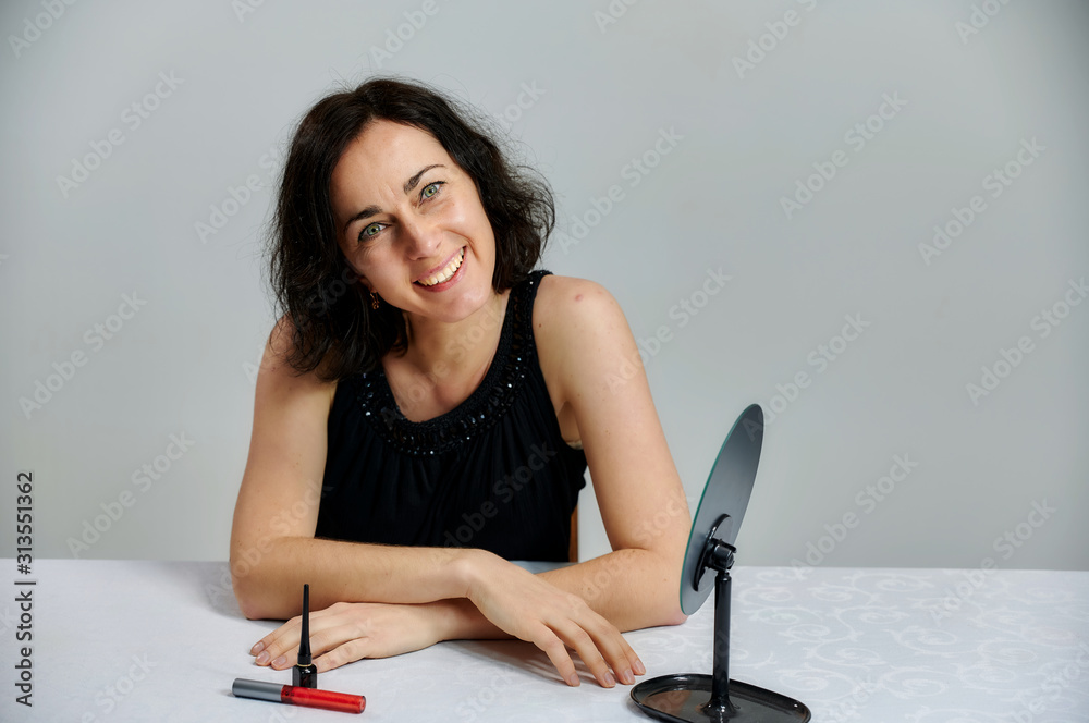 Portrait Of A Cute Smiling Talking Brunette Woman In A Black Dress On A White Background Sits