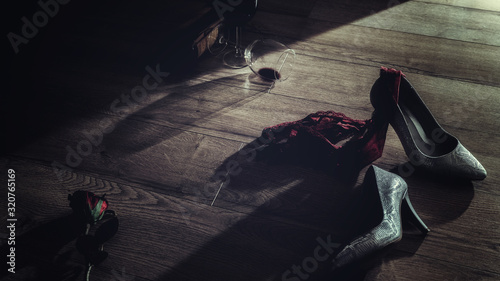Low key photography of red wine glasses and rose with high heel and panties thrown on the floor  romantic erotic lovers night