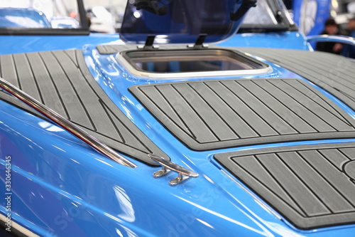 Gray marine teak on blue motor boat bow deck close up with opened porthole window