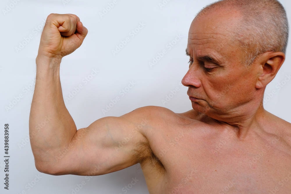 Old Man With A Naked Tanned Torso Senior Strains The Pumped Up Muscles Of The Arm Demonstrates