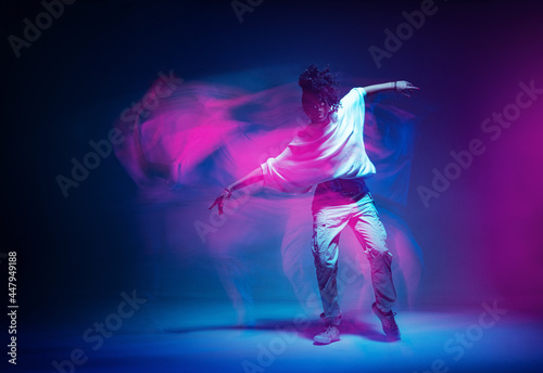 Stylish dancing modern girl moving in colorful neon studio light. Long exposure. Copy space