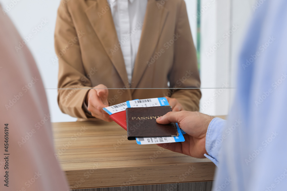 Man Giving Passports With Tickets To Agent At Check In Desk In Airport