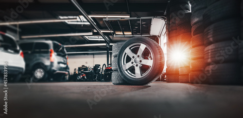 tire at repairing service garage background. Technician man replacing winter and summer tyre for safety road trip. Transportation and automotive maintenance concept