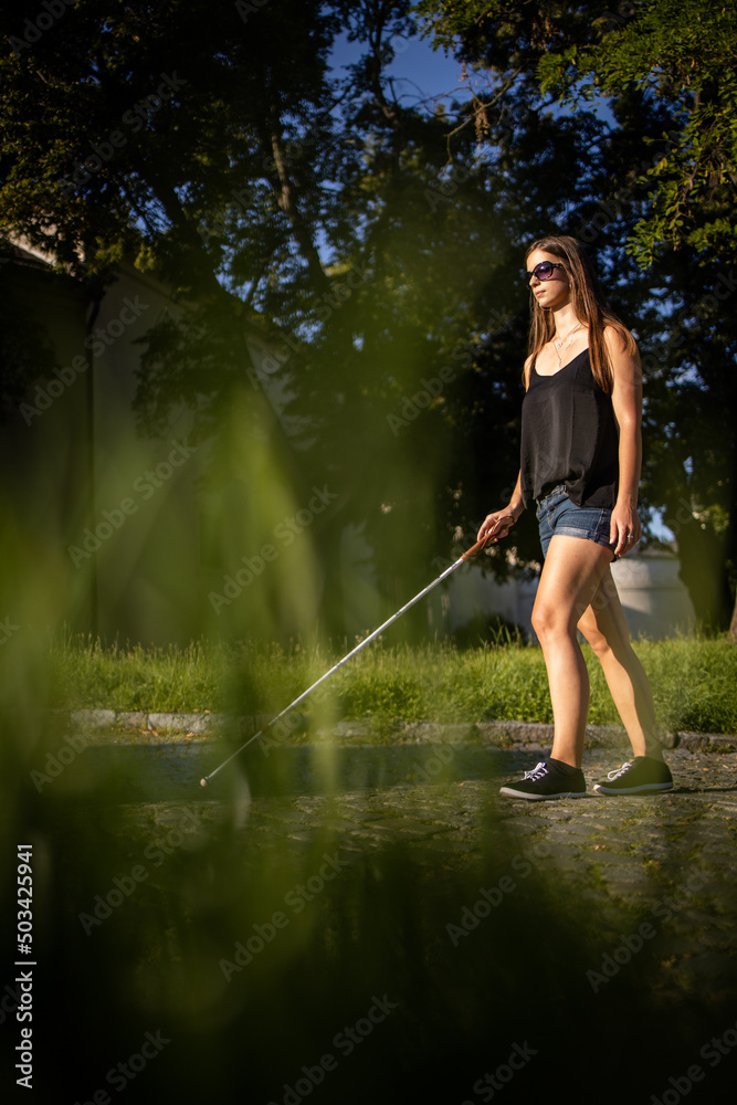 Blind Woman Walking On City Streets Using Her White Cane To Navigate