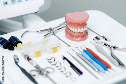 Tooth model with metal braces lying on a dental table with instruments