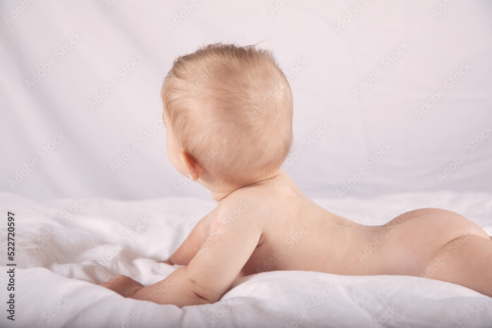 Cute Naked Baby Lies On His Stomach In Bed On A White Background Full