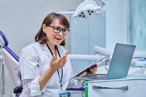 Doctor dentist working in office, using laptop, making video call conference