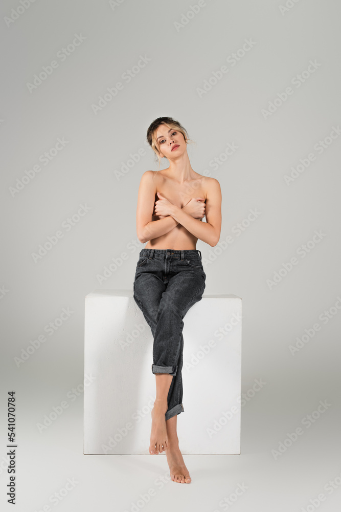 Full Length Of Barefoot And Half Naked Woman In Jeans Covering Bust