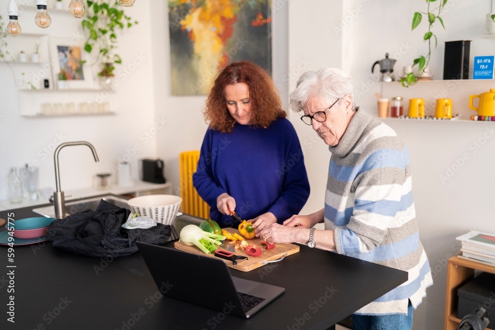 Smiling Redhead Mature Woman And Gray Haired Mother Cutting Fruits On Cutting Board While