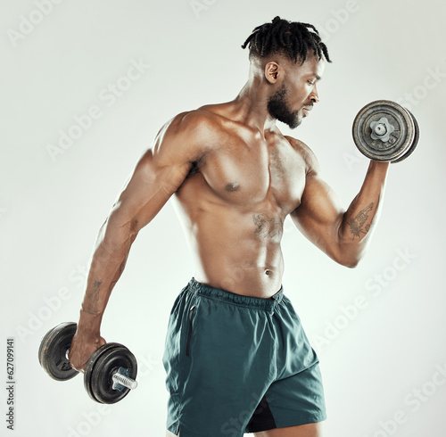 Fitness, strong and black man with dumbbells, exercise and wellness against studio background. Male person, model and bodybuilder with gym equipment, workout goal and strength with health and power