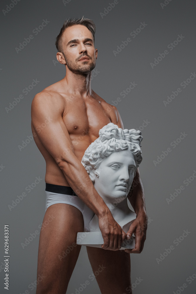 A Charismatic Male Model With A Sculpted Physique Poses Alongside A