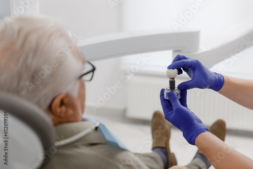 Professional dentist man treating cavities for a old man at the modern clinic he wearing special glasses for this treatment