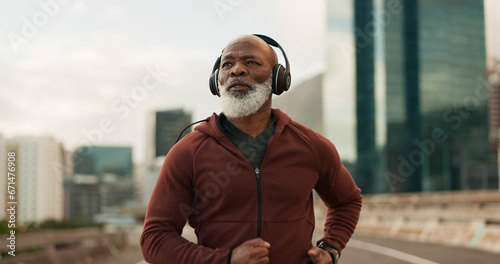Mature, athlete and running in city with headphones for fitness, workout or marathon training music. Black man, thinking or exercise podcast in South Africa for cardio wellness, health or sport radio