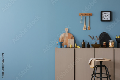 Interior design of kitchen interior with copy space, wooden cutboard, glass bottle, vase with flowers, vase with dried flowers, clock and personal accessories. Home decor. Template.