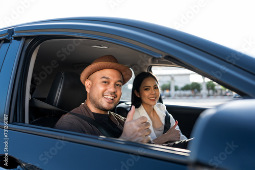 Young asian couple man and woman travel by car on a bright day beautiful blue sky sunlight. They was happy along the way trip. safety driving car vacation. Travel tourism vehicle.