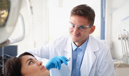 A woman at the reception of a male dentist examining