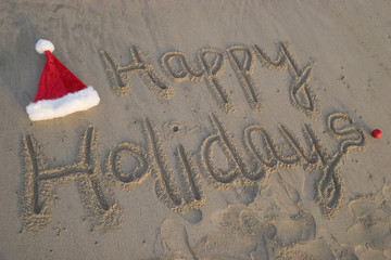 happy holidays written in sand