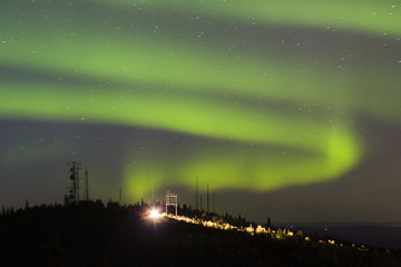 Wall Mural - aurora borealis over hill with antennas and car wi