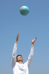 young asian man playing with a globe