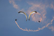 paragliders performing syncro sat with smoke trail