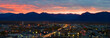sunset over Anchorage Alaska with buildings and traffic in the foreground and mountains silhouetted in bright colors behind.