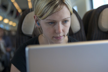 Young woman working on laptop computer aboard a train in Italy.