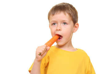 Wall Mural - five years old boy eating fresh carrot isolated on white