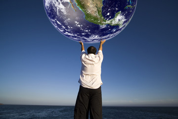 man with white shirt holding the planet earth