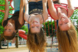 © Elenathewise - Three young girls hanging upside down in a park and laughing