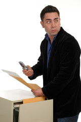 A man slipping documents out of a file cabinet a