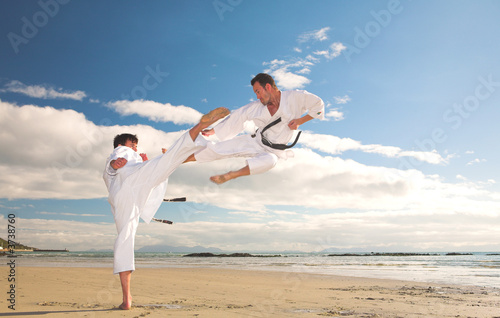 Fototapeta na wymiar Young adult men practicing Karate on the beach