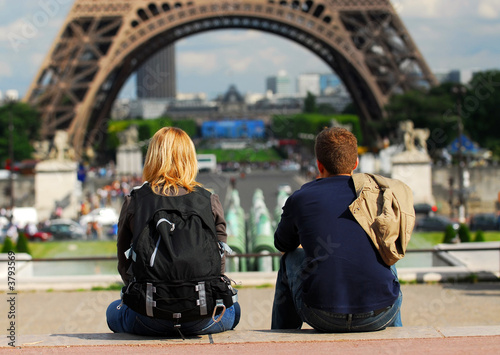 Fotografie, Obraz Young tourist couple sitting in front of Eiffel tower