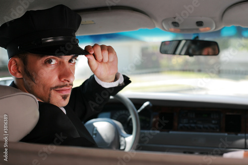 Fotografía Handsome male chauffeur sitting in a car saluting a viewer