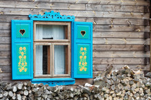 Opened Window With Decorative Colorful Shutters And Logs Below..