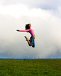 Happy young beautiful girl jumping in the green field.