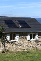 Les deux panneaux solaires sur le toit gris d'une maison ardéchoise