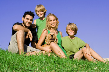 happy young family with pet dog outdoors