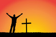 Silhouette of man and cross at sunset.