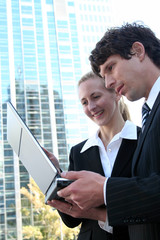 Wall Mural - Business couple using laptop outdoors