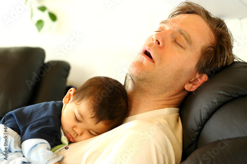 Fotografija  Father sleeping on chair with his baby boy on chest