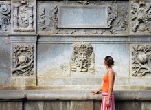 Tourist Woman In Orange By The Ancient Artistic Wall