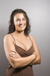 © iofoto - Portrait of brunette female with arms crossed smiling.