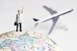 © David Crockett - Business figurine on earth globe with toy airplane